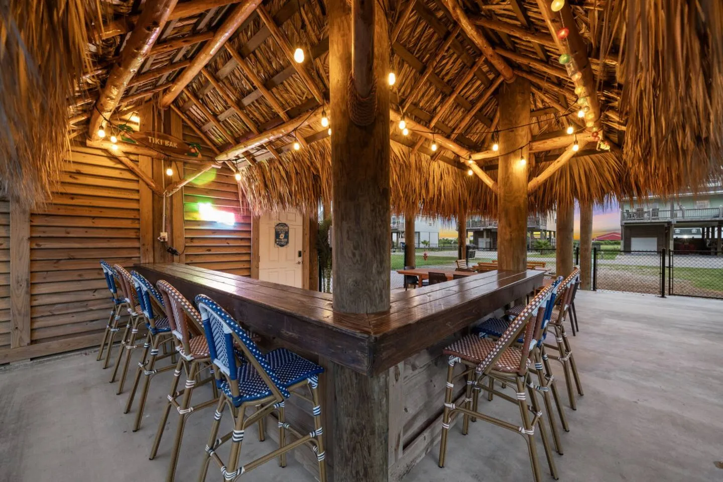 Covered tiki bar with seating, lights, and island-style hangout space.