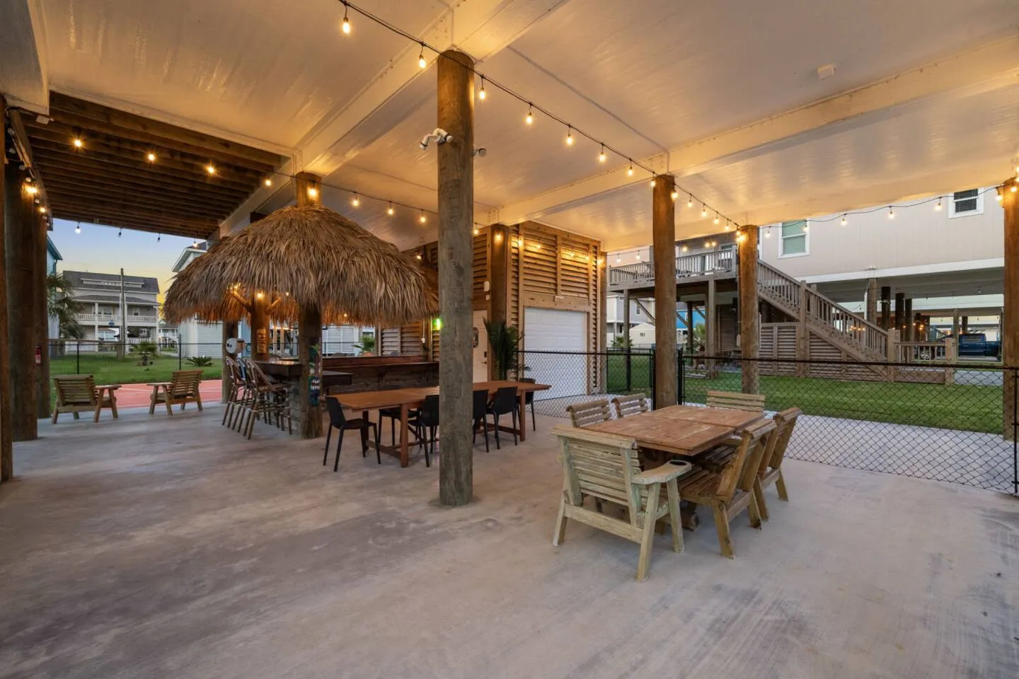 Covered patio with outdoor dining, tiki bar, and string lights.